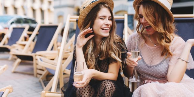 two girls sitting on chairs drinking champagne