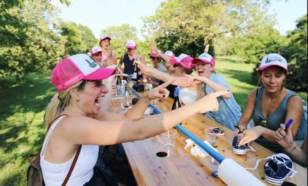 girls sitting outside in pink hats on wooden table