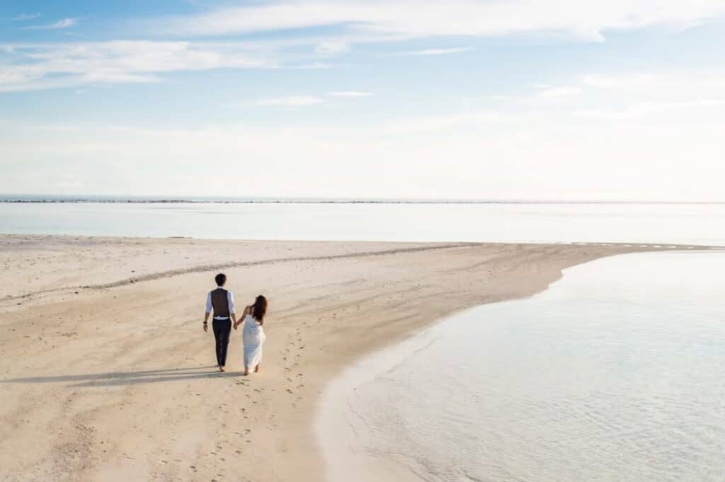 2 women and man walking on beach during daytime ph