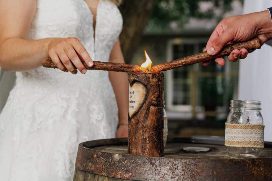 crop newlyweds lighting candle during ceremony · f