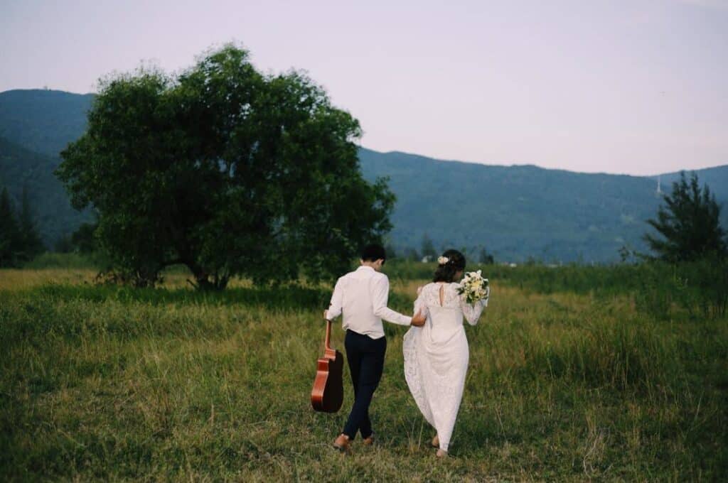 rear view of bride and groom walking in grassy fie